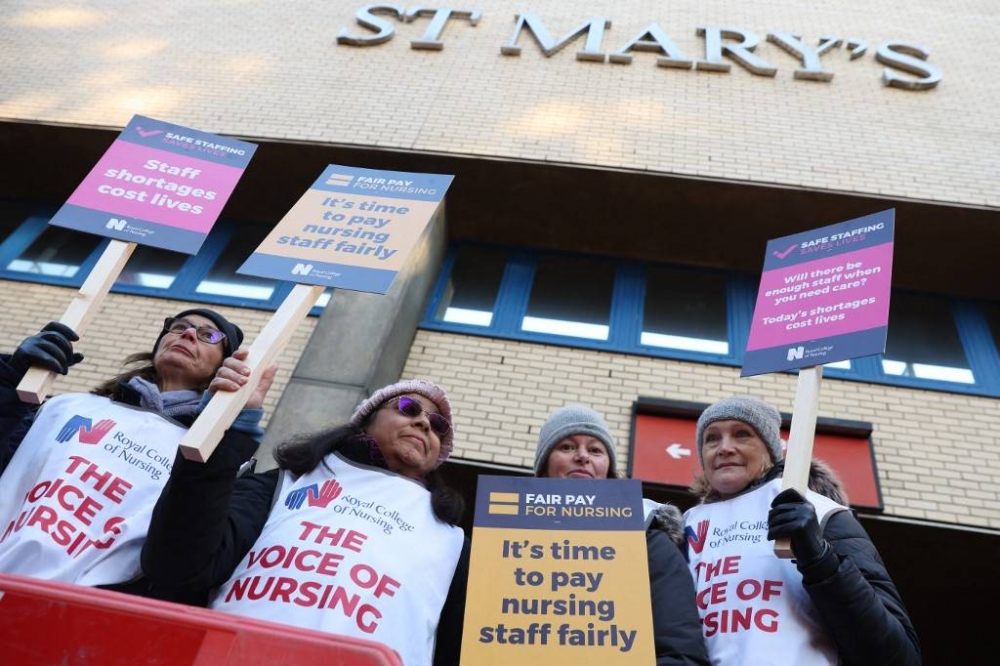 Healthcare workers hold placards at a picket line outside St Mary's Hospital in west London on December 15, 2022. UK nurses staged an unprecedented one-day strike as a ‘last resort’ in their fight for better wages and working conditions, despite warnings it could put patients at risk. — AFP pic