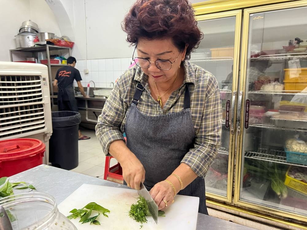 Beh Gaik Lean slicing ‘ulam’ leaves for ‘nasi ulam’. — Picture by Opalyn Mok 