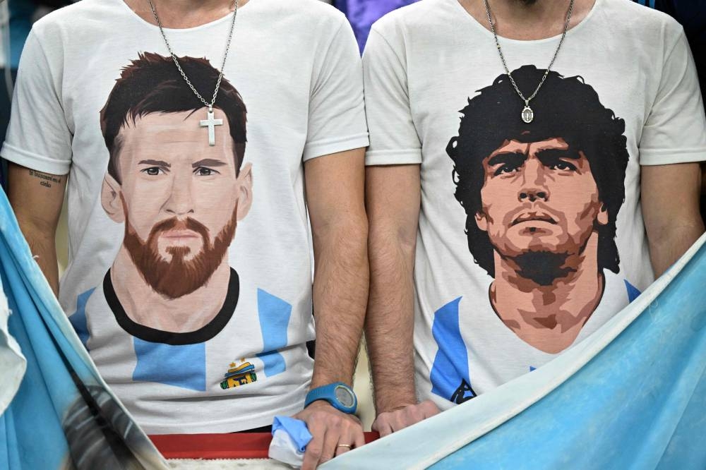 Supporters of Argentina, wearing t-shirts with images of Argentine stars Lionel Messi and late Diego Maradona, wait on the stands ahead of the Qatar 2022 World Cup football semi-final match between Argentina and Croatia at Lusail Stadium in Lusail, north of Doha on December 13, 2022. — AFP pic