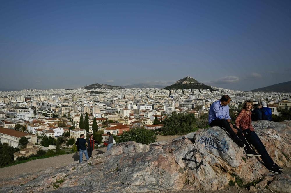 Tourists enjoy the views of Athens on the Aeropagus Hill in Athens, beneath the Acropolis on December 8, 2022.— AFP pic