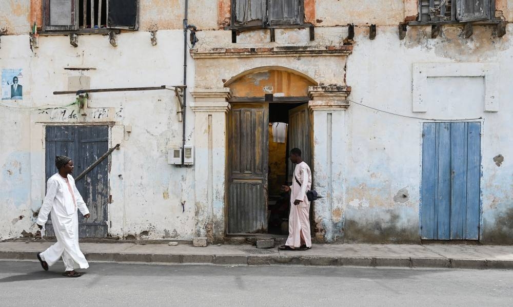 People walk on a street past dilapidated buildings, in Saint-Louis on October 11, 2022, a long period of political and economic decline that has left many historic architecture and other cultural heritage sites in a state of disrepair. — AFP pic