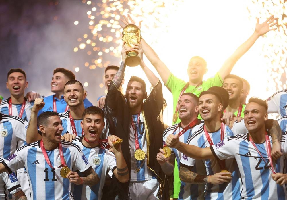 Argentina's Lionel Messi (centre) lifts the Fifa World Cup Trophy as he celebrates with teammates winning the Qatar 2022 World Cup final football match against France at the Lusail Stadium in Lusail December 18, 2022. — Reuters pic
