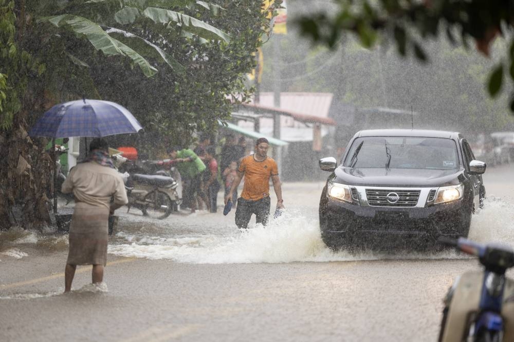 People wade in flood water following heavy rain at Kampung Kubang Kual in Rantau Panjang December 18, 2022. State health director Datuk Dr Zaini Hussin said ten hospitals in Kelantan are still operating as usual and not affected by the monsoon floods. — Bernama pic