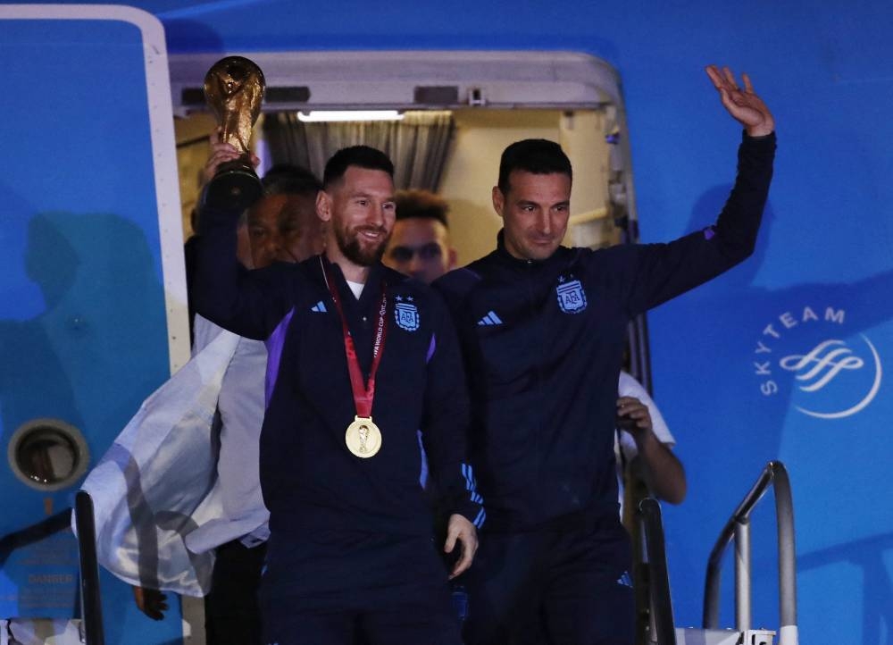 Argentina coach Lionel Scaloni and Lionel Messi with the World Cup trophy during the team's arrival at Ezeiza International Airport in Buenos Aires December 20, 2022. — Reuters pic