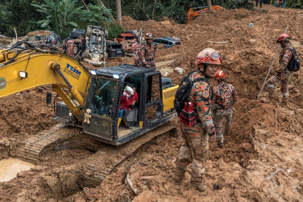 Fire Department personnel near an excavator that is used for rescue operations. — Picture by Shafwan Zaidon