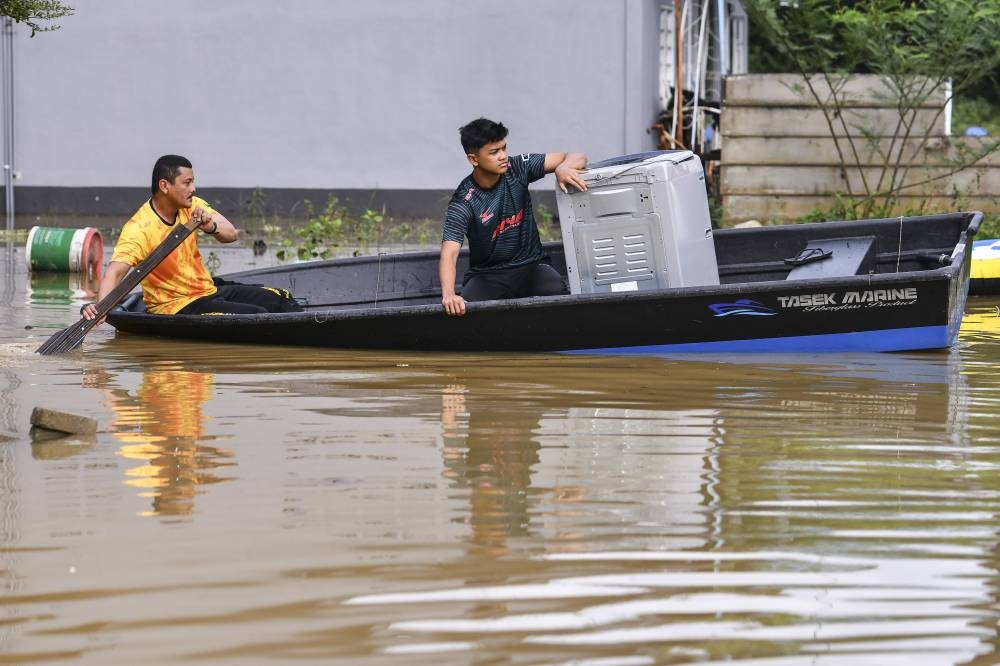 Flood victims are seen with a washing machine aboard their boat in Kampung Jeram, Kuala Terengganu December 21, 2022. — Bernama pic
