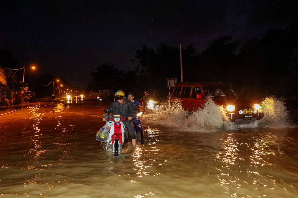 Motorists drive through floodwaters at night near Sungai Paka which began to recede on the main Dungun-Kuala Terengganu road near Kampung Nyior, Paka, Terengganu, December 22, 2022. — Bernama pic