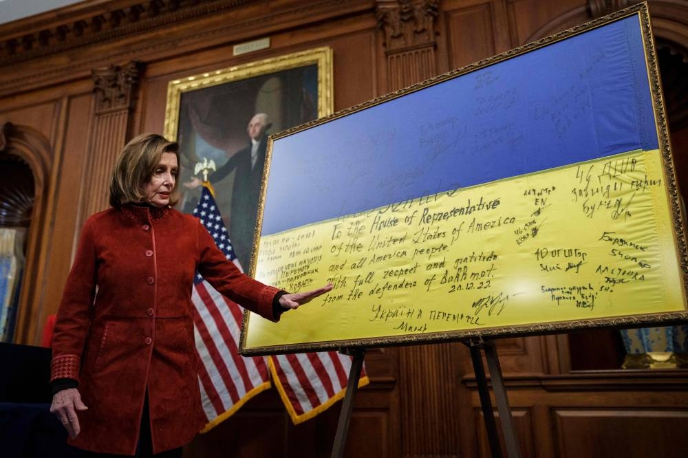 Speaker of the House Nancy Pelosi (D-CA) stands next to and speaks about a Ukrainian flag signed by members of the Ukrainian military that was gifted to the Congress from President of Ukraine Volodymyr Zelensky, following a bill enrolment ceremony for the National Defence Authorisation Act (NDAA) at the US Capitol on December 22, 2022 in Washington, DC. — Drew Angerer/Getty Images/AFP pic
