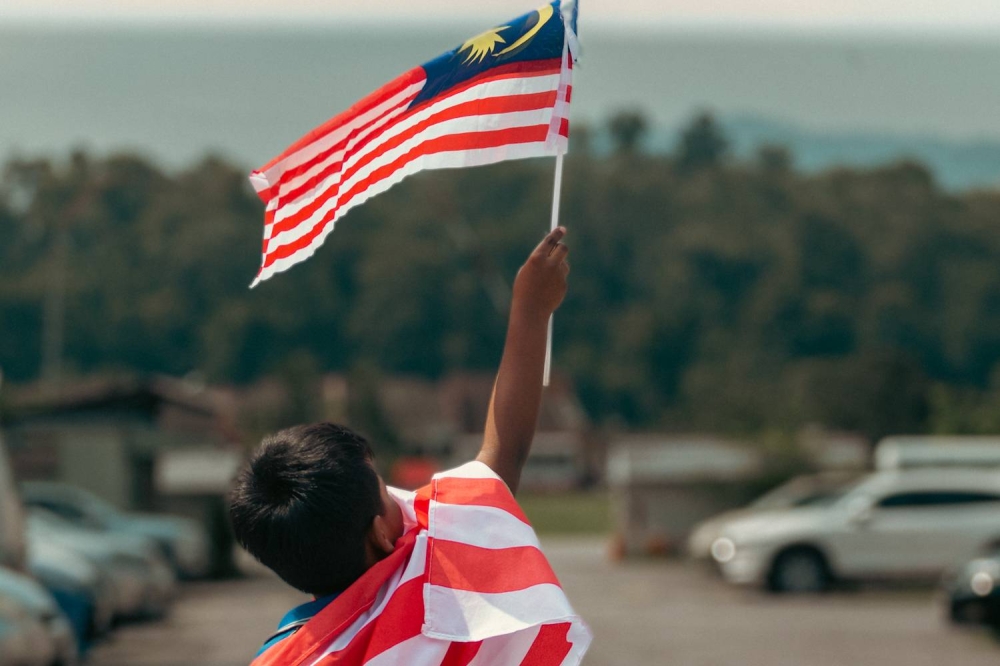 A boy waves the national flag in a park at Cheras August 10, 2022. — Picture by Devan Manuel