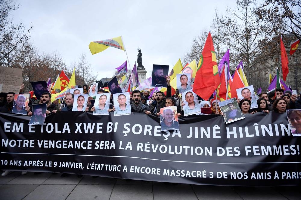 Protesters hold Kurdish workers party (PKK) flags and portraits of victims during a demonstration of supporters and members of the Kurdish community, a day after a gunman opened fire at a Kurdish cultural centre killing three people, at The Place de la Republique in Paris on December 24, 2022. — AFP pic