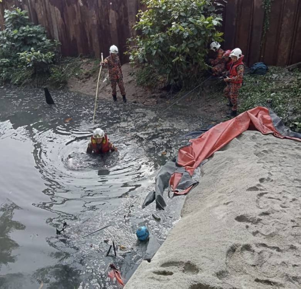 Rescue personnel attempting to locate the lorry driver in the ditch at the Rapid Transit System Link (RTS Link) project site in Stulang Laut in Johor Baru December 24, 2022. — Picture courtesy of the Johor Fire and Rescue Department