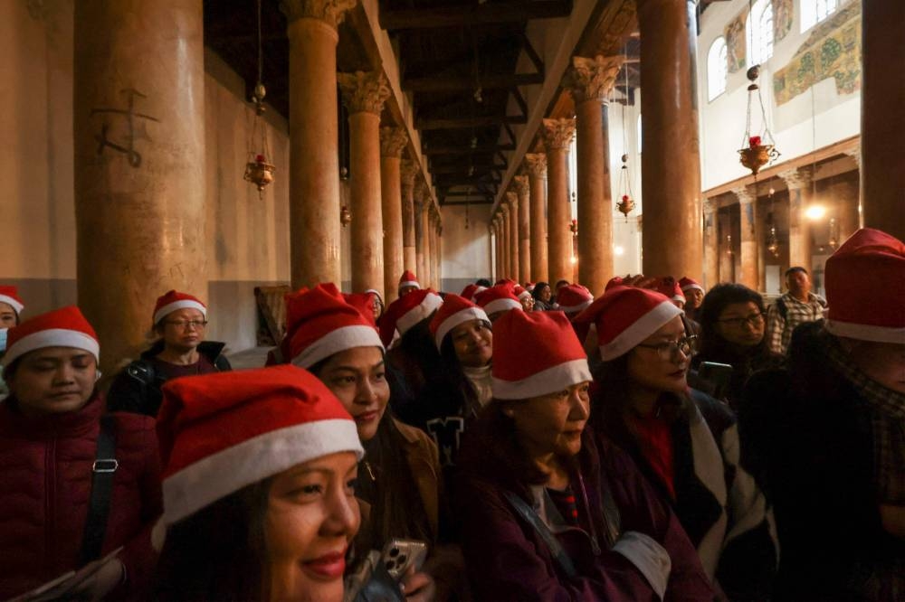 Tourists and pilgrims visit the Church of the Nativity in the biblical West Bank city of Bethlehem on December 24, 2022. — AFP pic