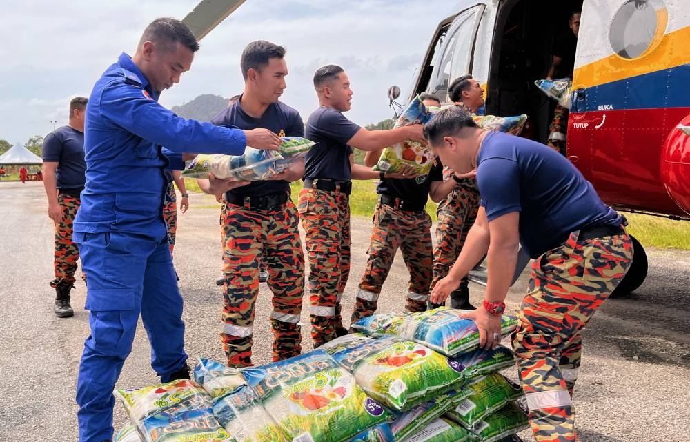 Members of the Malaysian Fire and Rescue Department (JBPM) and the Malaysian Civil Defense Force (APM) lifting rice to be sent to the Orang Asli settlement in Gua Musang district after several roads become impassable due to the log path being badly damaged by rain, December 25, 2022. — Bernama pic