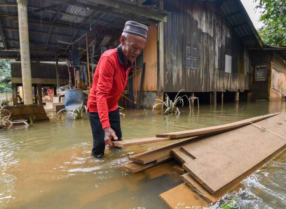 Villager Che Ali Che Mud, 60, inspecting the wooden boards that will be used to repair his house following the recent flood incident during a survey of Kampung Tersang, Rantau Panjang December 26, 2022. — Bernama pic