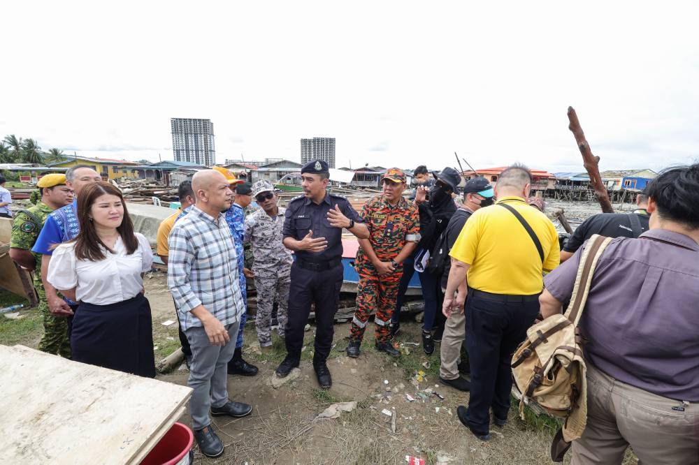 Datuk Armizan Mohd Ali is briefed by Sandakan police chief Abdul Fuad Abdul Malek (centre) during a visit to flood-hit Kampung Forest December 27, 2022. — Bernama pic