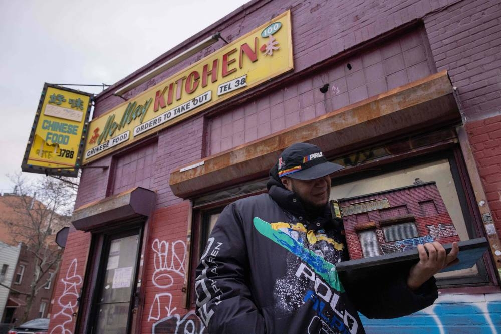 Danny Cortes, a street miniature artist, holds a miniature of Ho May Kitchen in the Brooklyn borough of New York City on December 19, 2022. — AFP pic