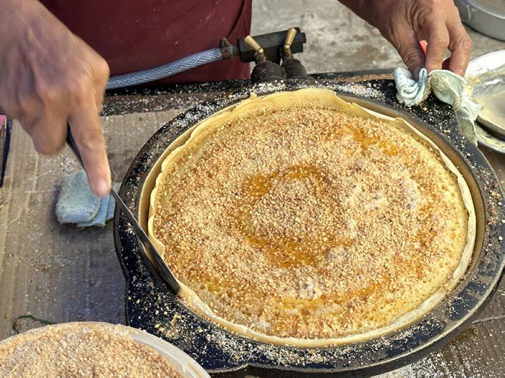 The pancake is topped with roasted ground peanuts drizzled with melted Planta.