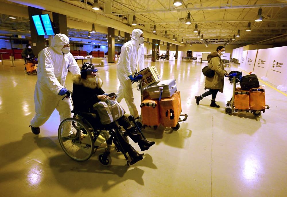 Workers wearing protective masks and suits help Chinese travellers leaving the arrival hall of Rome–Fiumicino International Airport, near Rome, on December 29, 2022 after being tested for Covid-19. — AFP pic