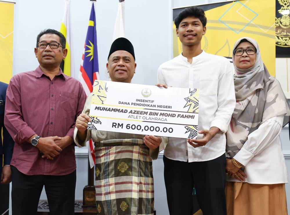 Datuk Seri Saarani Mohamad hands over a mock cheque to sprinter Muhammad Azeem Mohd Fahmi at the Perak Darul Ridzuan building in Ipoh December 30, 2022. ― Bernama pic