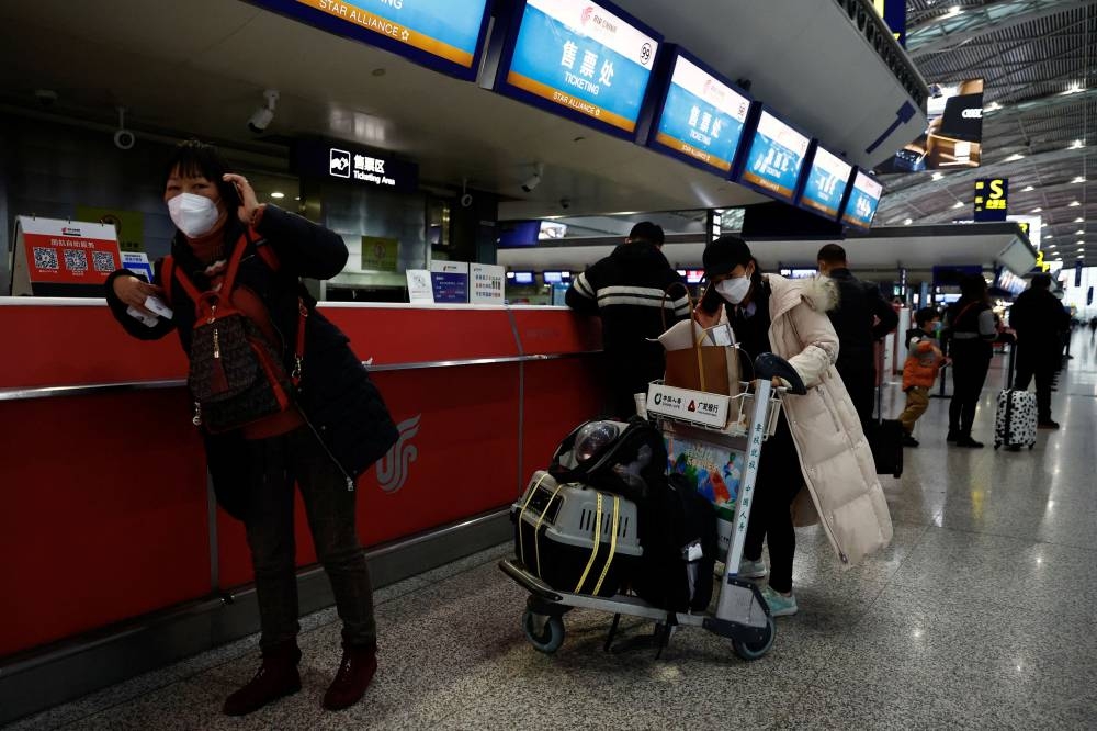 Travellers stand at a ticketing counter at Chengdu Shuangliu International Airport in Chengdu December 30, 2022. ― Reuters pic