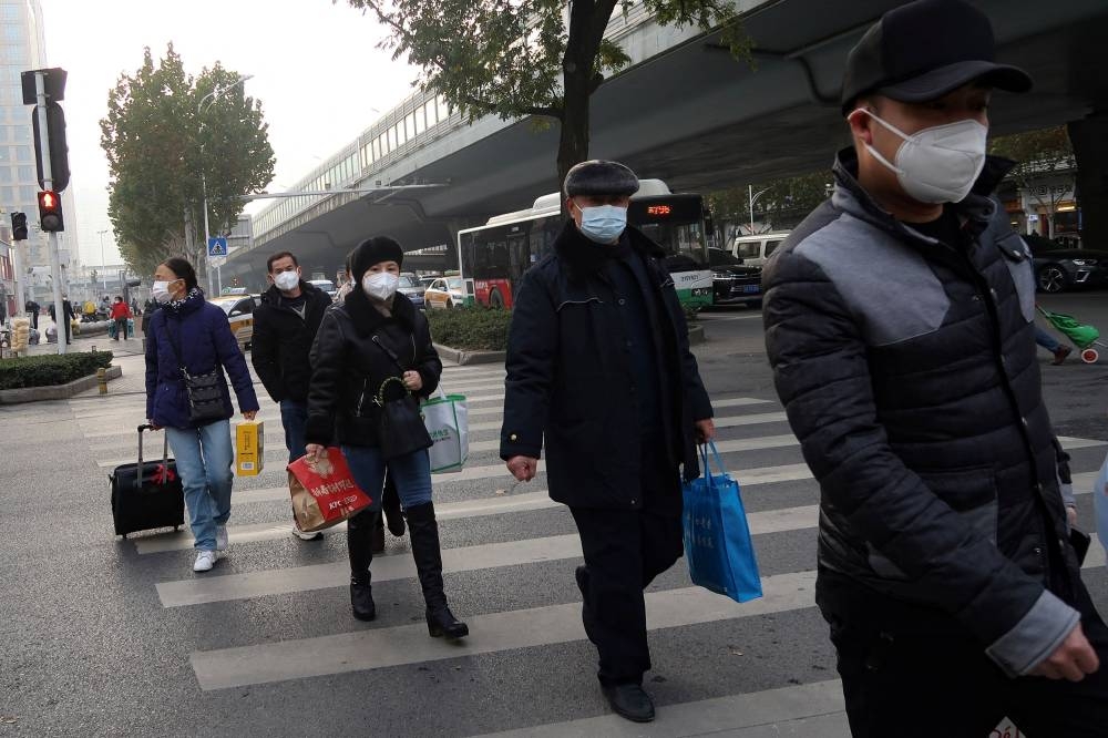 People cross a road in Wuhan, Hubei province, China December 31, 2022. ― Reuters pic