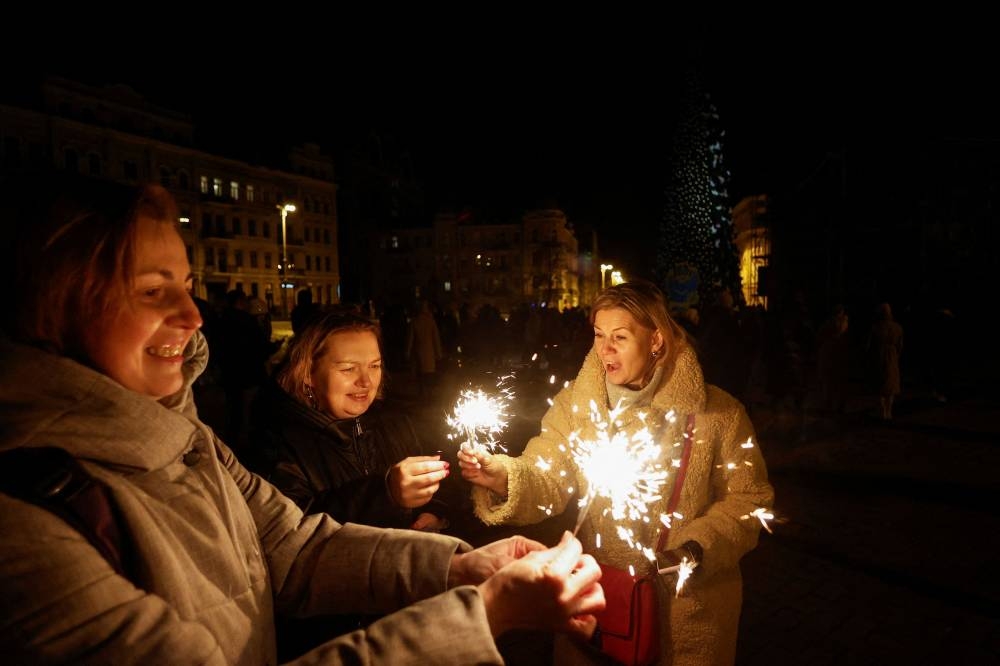 Women hold bengal fires next to a Christmas tree during a celebration the New Year eve before a curfew, amid Russia's attack on Ukraine, in front of the St Sophia Cathedral in Kyiv December 31, 2022. — Reuters pic