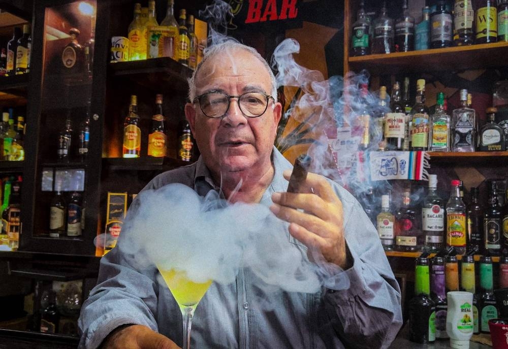 Master bartender Jose Rafa Malen blows tobacco smoke to an original daiquiri (without ice) at the Bartenders Association in Havana on December 22, 2022. — AFP pic