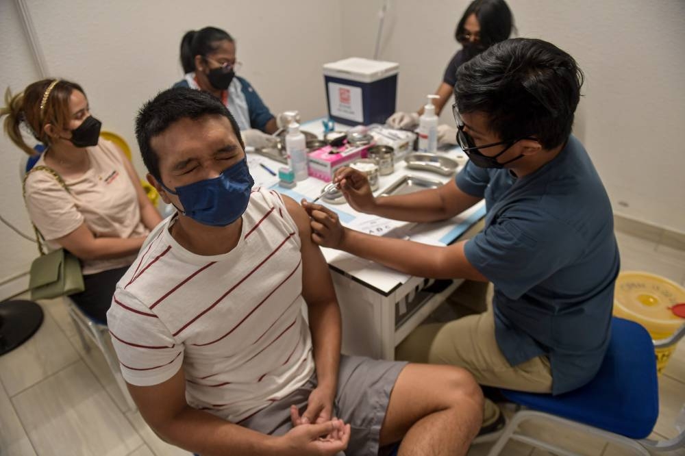 A man reacts as he receives his Covid-19 booster dose in Kuala Lumpur on February 20, 2022. — Bernama pic