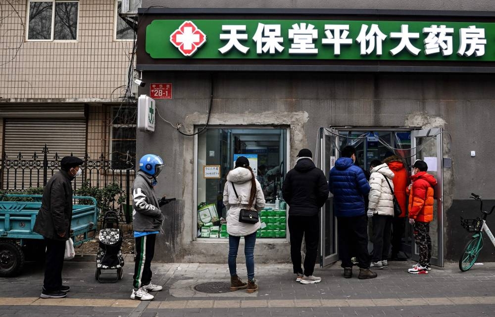 This file photo taken on December 9, 2022 shows people queueing to buy medicine amid the Covid-19 pandemic at a drug store in Beijing. — AFP pic
