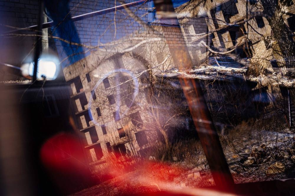 A partially destroyed residential building is reflected in a Soviet Union build car window in Chasiv Yar, Donetsk region, on January 7, 2023, amid Russia's military invasion on Ukraine. — AFP pic