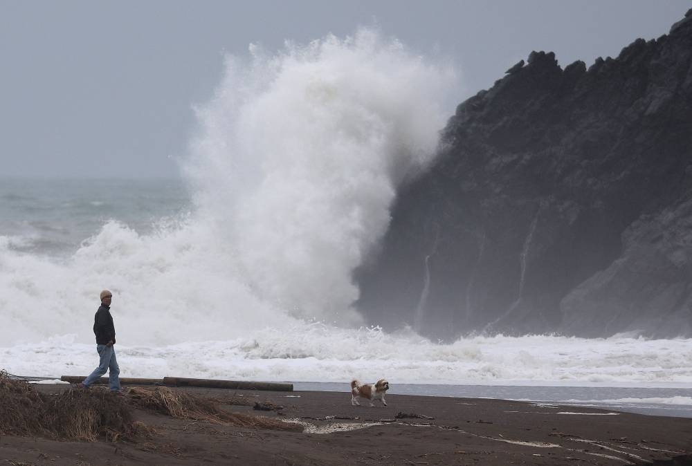 A man walks his dog on the beach as a large wave crashes into shore at Rodeo Beach on January 07, 2023 in Sausalito, California. The San Francisco Bay Area continues to get drenched by powerful atmospheric river events that have brought high winds and flooding rains. — Justin Sullivan/Getty Images/AFP pic