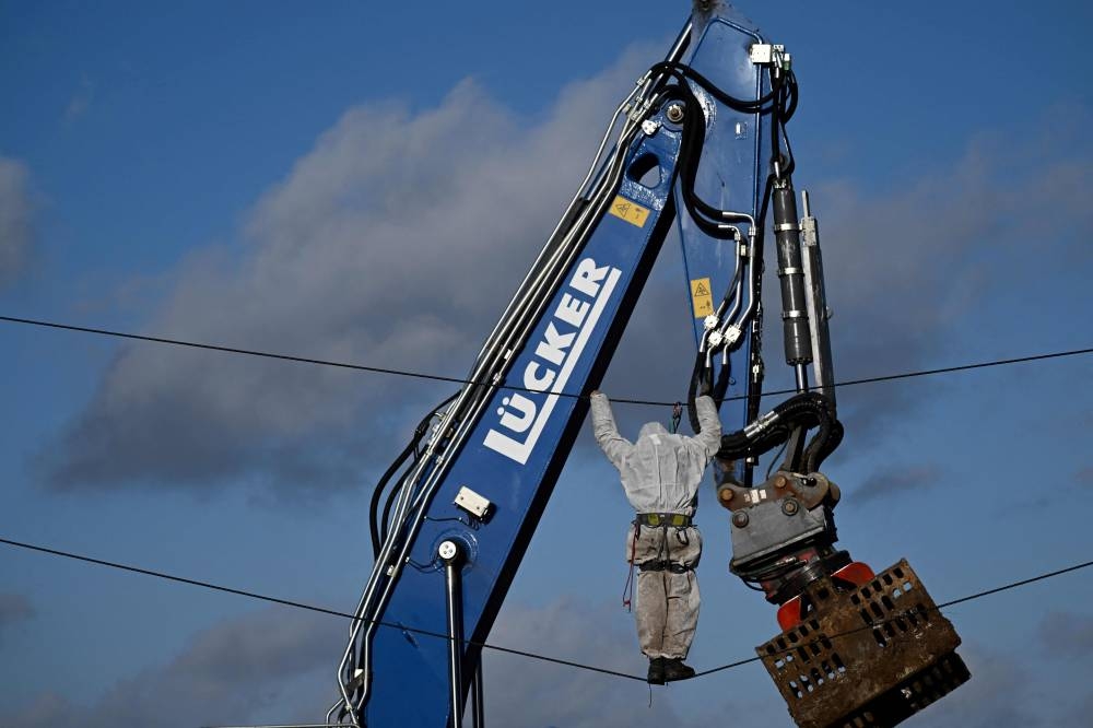 An activist moves on a rope as policemen evacuate the village of Luetzerath, western Germany, on January 11, 2023, ahead of a planned demolition to expand a nearby coal mine. — Reuters pic