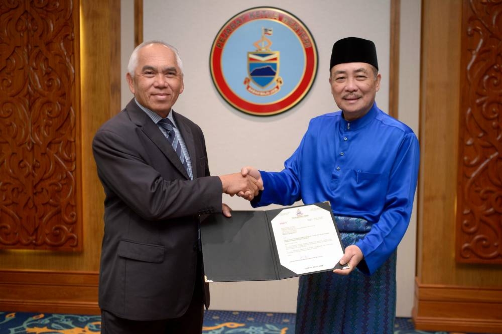Sabah Chief Minister Datuk Seri Hajiji Noor (right) hands Datuk Yusof Yacob his appointment letter as the chairman of state investment arm Qhazanah Sabah Bhd, at Kota Kinabalu January 13, 2023. — Bernama pic 