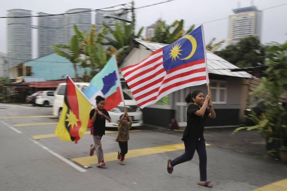Children hold up Sarawak, Sabah and Malaysia flags as they run along Jalan Datuk Abdullah Yassin in Kampung Baru September 15, 2018. — Picture by Yusof Mat Isa