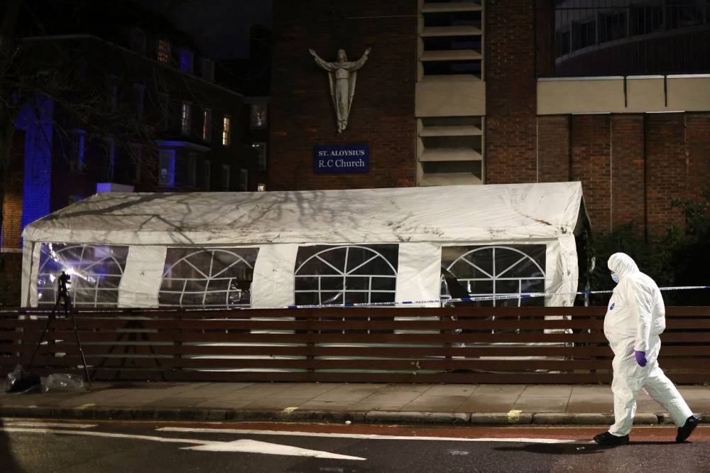 Forensics officer walks next to police officers at the scene of a shooting, the attack reportedly happened during a funeral at St Aloysius Church, in London, Britain, January 14, 2023. — Reuters pic