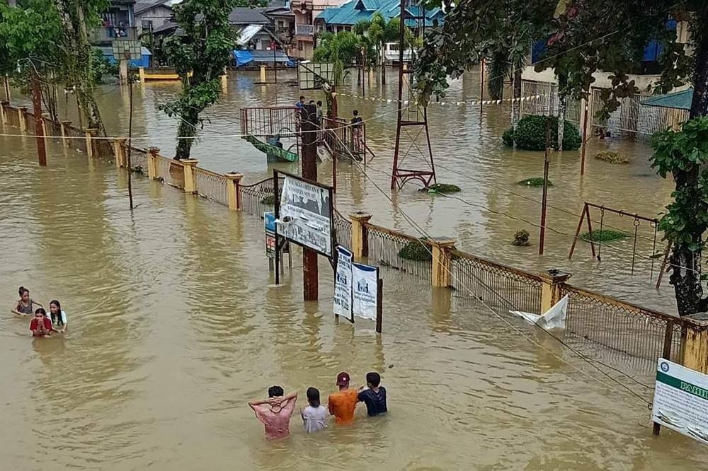 This handout photo taken on January 11, 2023 and received from Jipapad Mayor Benjamin Ver shows residents wading through a flooded road in Jipapad town, Eastern Samar province. — Mayor Benjamin Ver handout pic via AFP