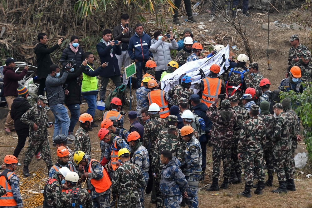 Rescuers pull the body of a victim who died in a Yeti Airlines plane crash in Pokhara January 16, 2023. — AFP pic