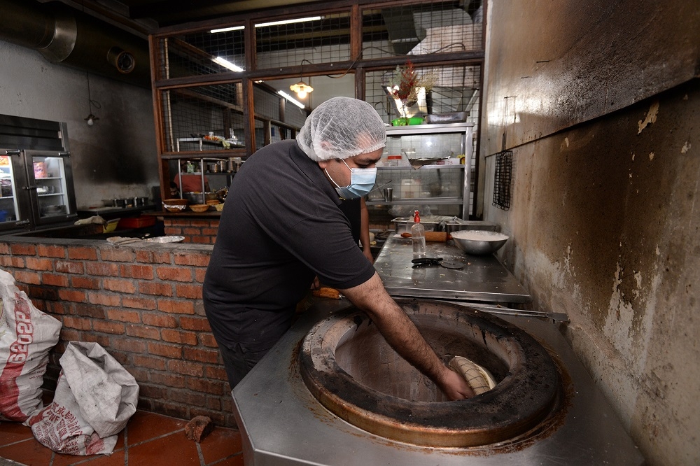 The chef at Sardaarji making the naan in a charcoal tandoori oven.