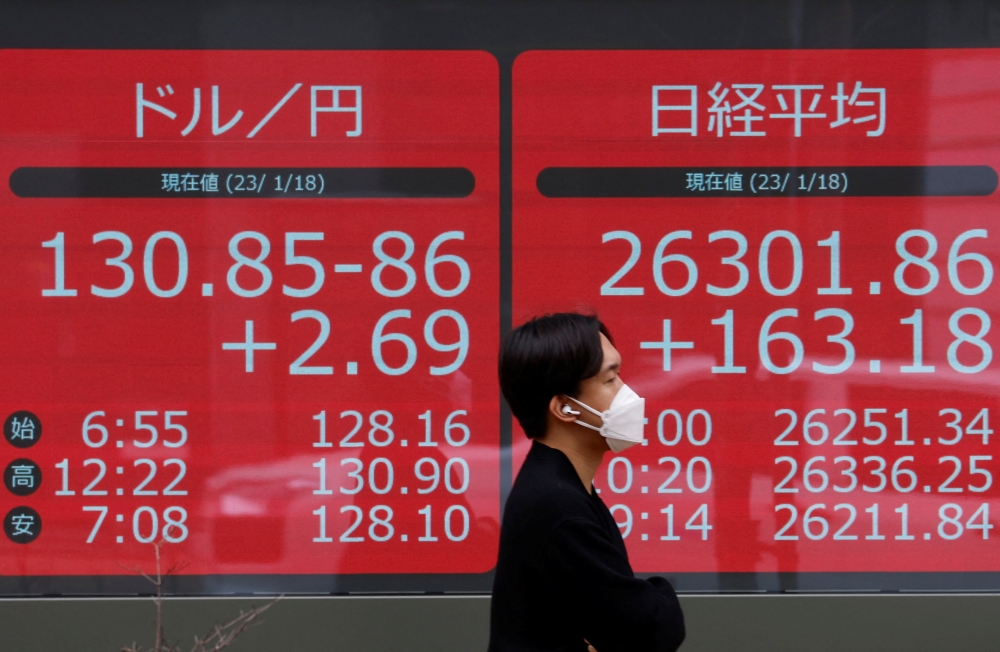 A man walks past electric monitors displaying Japan's Nikkei share average and the exchange rate between the Japanese yen against the US dollar outside a brokerage in Tokyo January 18, 2023. — Reuters pic