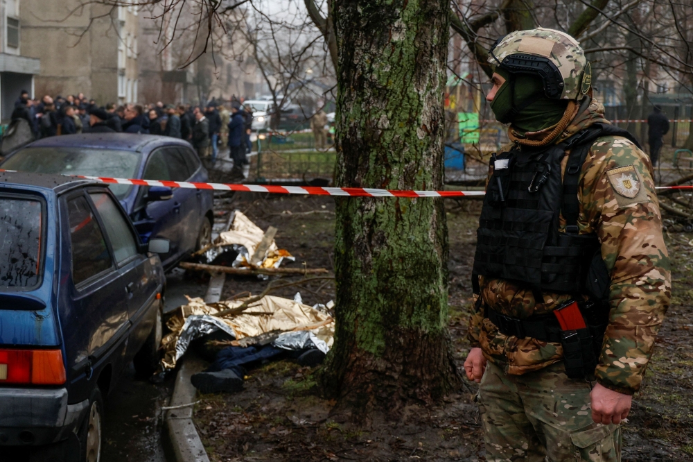 A serviceman stands guard near dead bodies at the site where a helicopter falls on civil infrastructure buildings, amid Russia's attack on Ukraine, in the town of Brovary, outside Kyiv, Ukraine, January 18, 2023. — Reuters pic