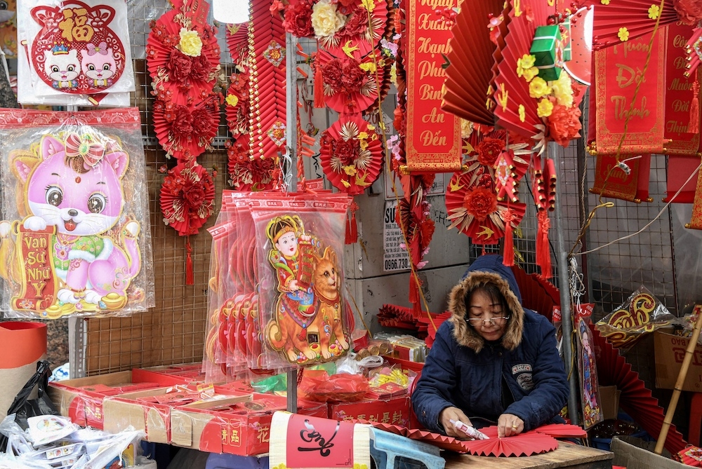 This photograph taken on January 17, 2023 shows a shopkeeper at a stall that is selling cat images ahead of the lunar new year at a market in the old quarters of Hanoi. — AFP pic