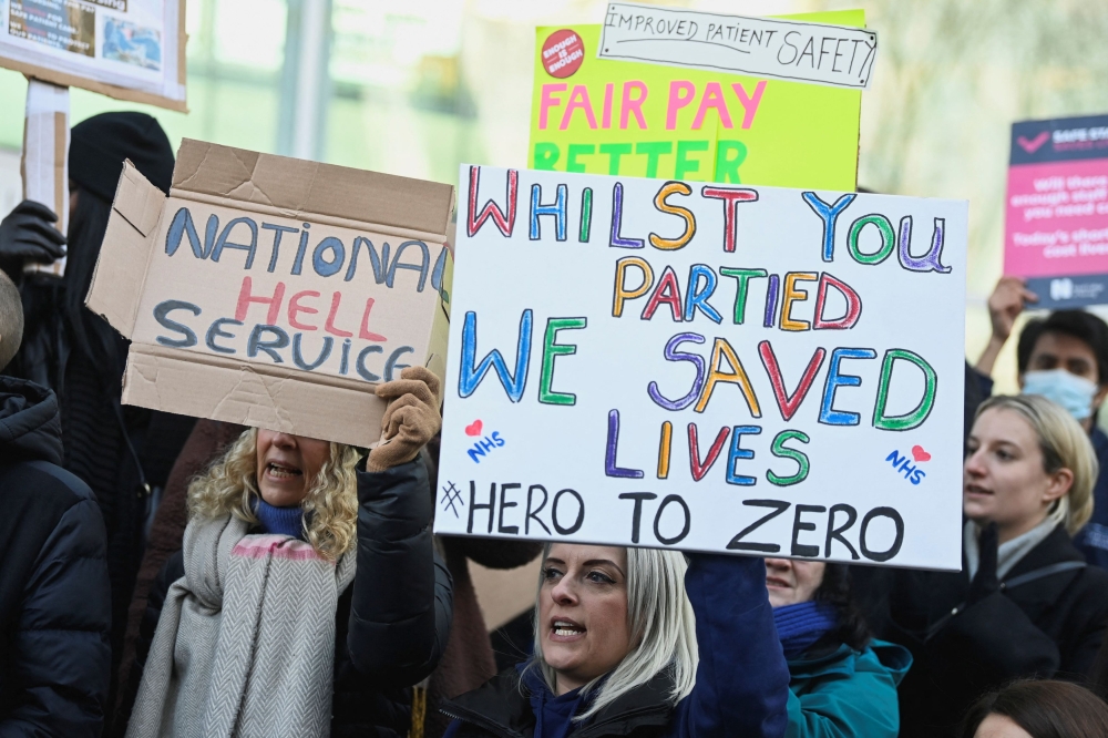 लंदन, ब्रिटेन में 18 जनवरी, 2023 को वेतन को लेकर सरकार के साथ विवाद के बीच एनएचएस नर्सों ने हड़ताल के दौरान बैनर पकड़े। - रॉयटर्स तस्वीर