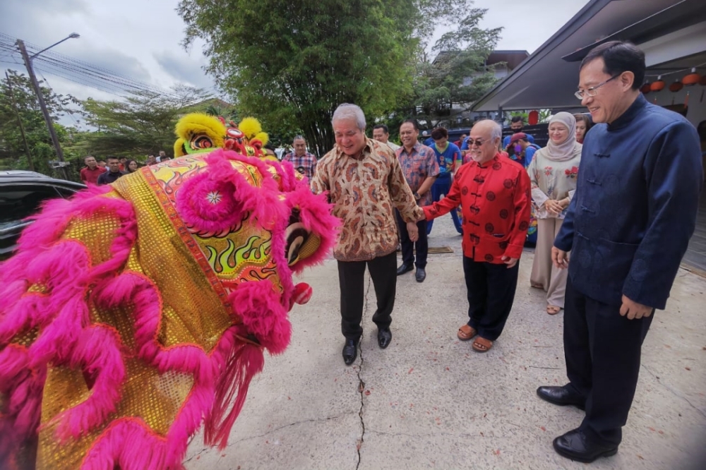 Awang Tengah (left) being welcomed by Liew (second, right) during his CNY open house yesterday. ― Borneo Post pic