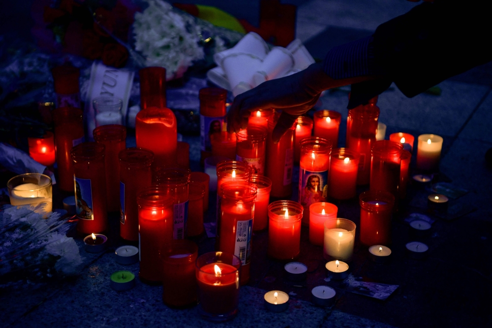 People light candles and lay flowers after an attack in a church in Alta square, in Algeciras, southern Spain, on January 26, 2023. — AFP pic
