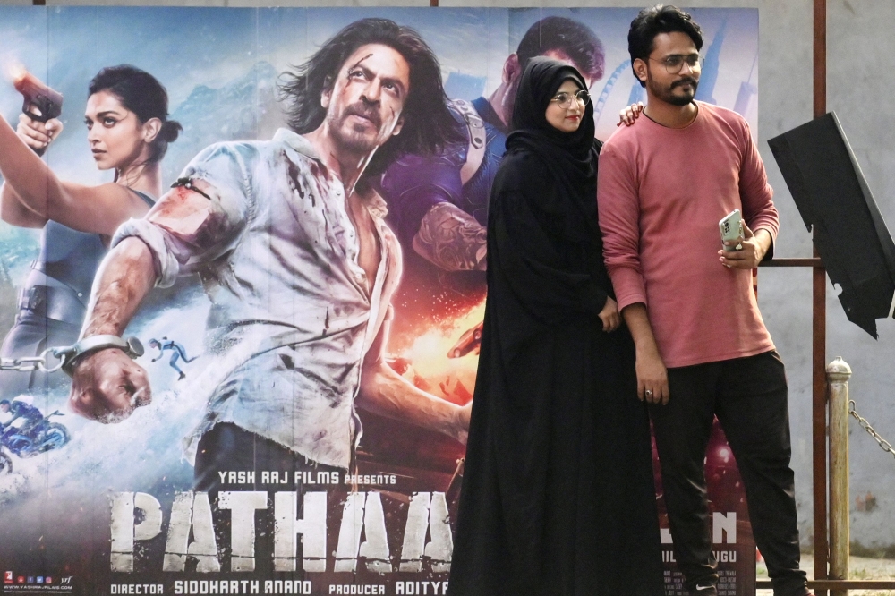 Moviegoers pose for pictures in front of a poster of the Bollywood movie 'Pathaan' outside a cinema hall in Prayagraj on January 25, 2023. — AFP pic