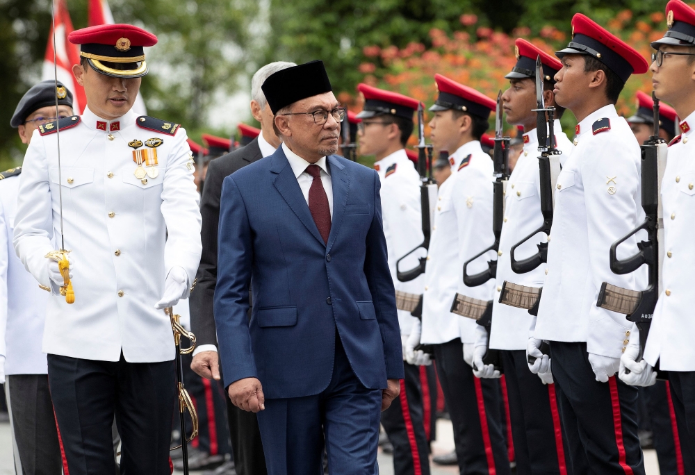 Prime Minister Datuk Seri Anwar Ibrahim and his Singapore counterpart Lee Hsien Loong review honor guards during a welcome ceremony at the Istana, or Presidential Palace in Singapore 30 January 2023. — Picture by  How Hwee Young/Pool via Reuters