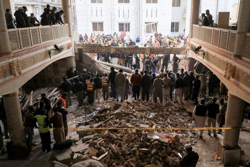 People and rescue workers gather to look for survivors under a collapsed roof, after a suicide blast in a mosque in Peshawar, Pakistan January 30, 2023. — Reuters pic