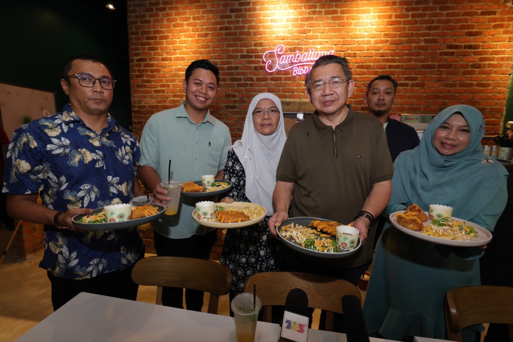 Domestic Trade and Cost of Living Minister who is also Pulai Member of Parliament Datuk Seri Salahuddin Ayub (third right) with Samballana Bistro owner Muhammad Akmal (second, left), 24, and Suhana Mohd Esa (right) , 48, shows the Rahmah Menu priced at RM5 along with water sold at Samballana Bistro Bandar Dato' Onn in Johor Baru, February 4, 2023. — Bernama pic