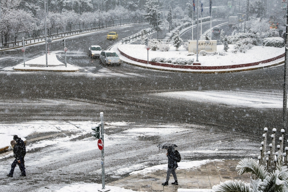 People and vehicles make their way, during snowfall in Athens, Greece, February 6, 2023. — Reuters pic
