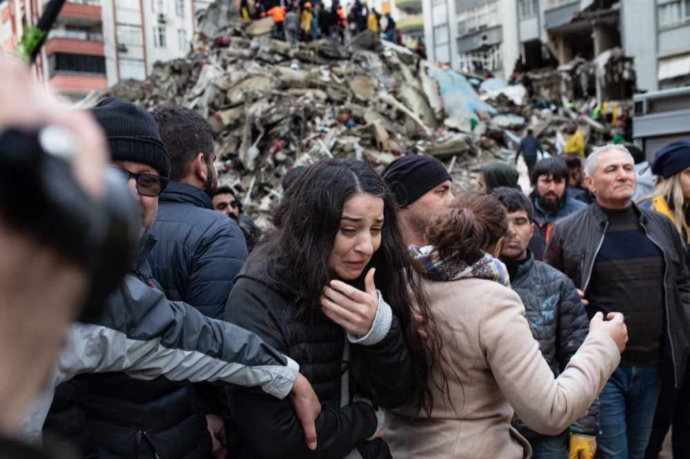 A woman reacts as rescuers search for survivors through the rubble of collapsed buildings in Adana, on February 6, 2023 after a 7,8 magnitude earthquake struck the country’s south-east. — AFP pic
